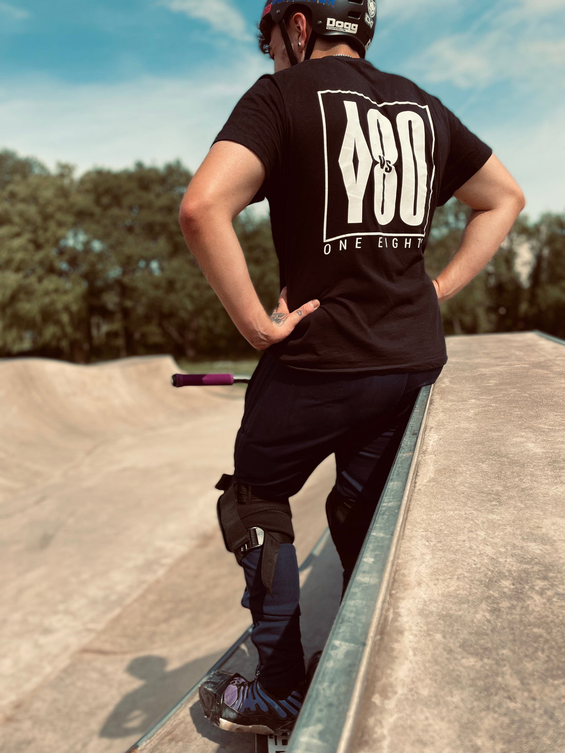 Teenager standing in a skatepark with a stunt scooter.