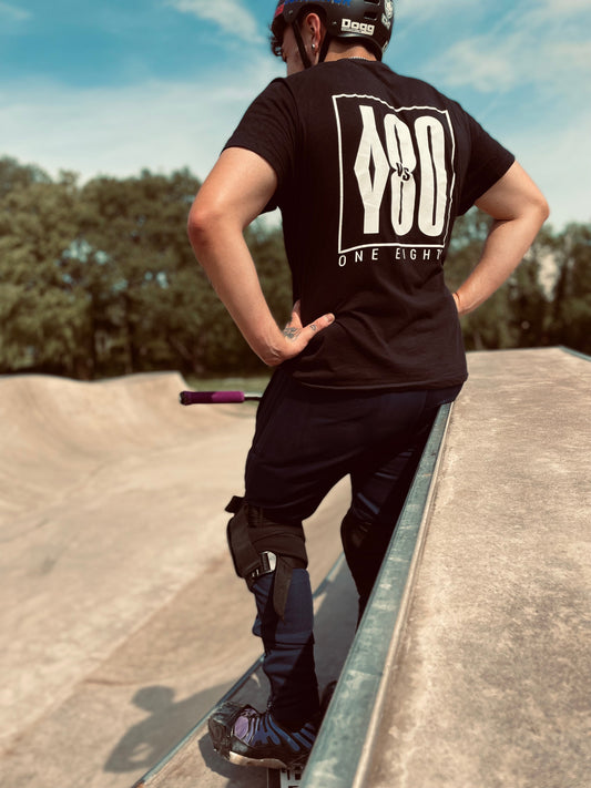 Teenager standing in a skatepark with a stunt scooter.
